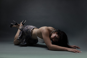 Bandfoto Laura Oliveira: Musikerin in künstlerischer Pose
Eine Musikerin liegt auf dem Boden eines Studios und stützt sich mit einem Arm ab. Sie trägt ein helles Oberteil und einen dunklen Rock. Der neutrale Hintergrund und die reduzierte Beleuchtung verleihen der Aufnahme einen künstlerischen Charakter.