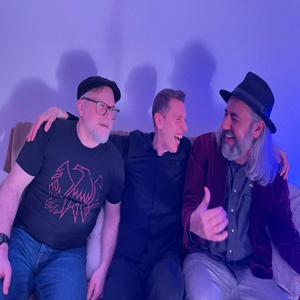3 Musiker lachend vor blauer Wand